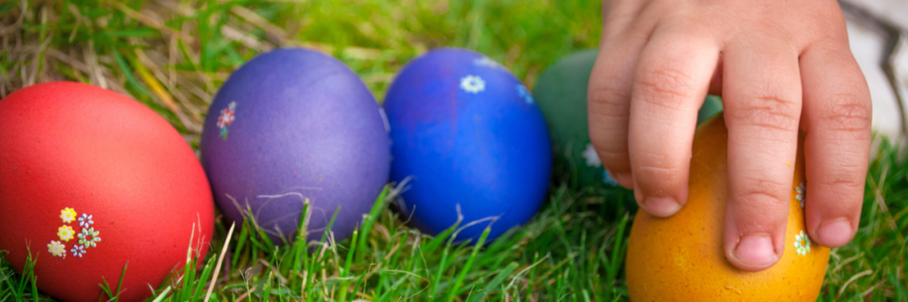 Child's hand picking up colored eggs