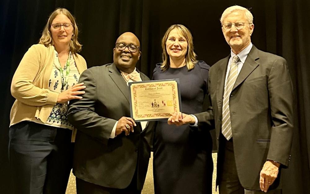 Four people smiling and holding an award.