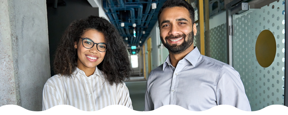 two people in office space smiling looking forward