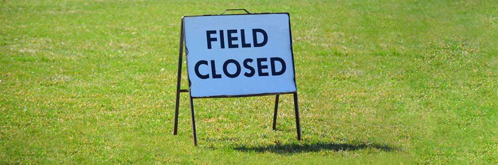 grass field with field closed pop up sign