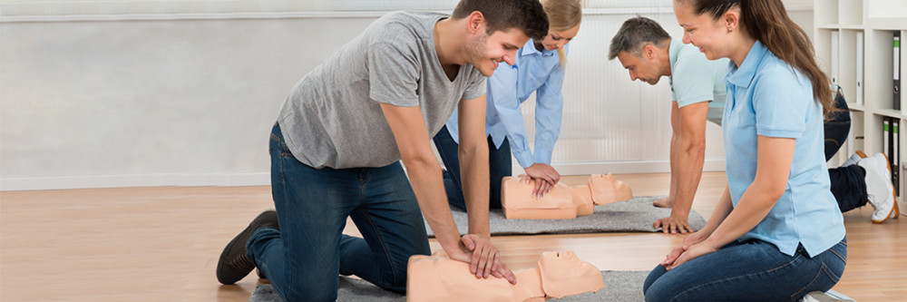 Four people practice CPR on a training dummy during an emergency preparedness class