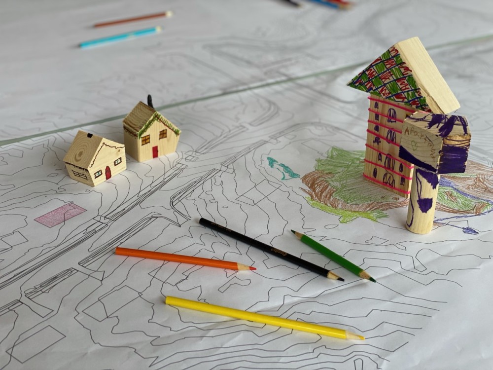Image of a map, color pencils, and tiny houses