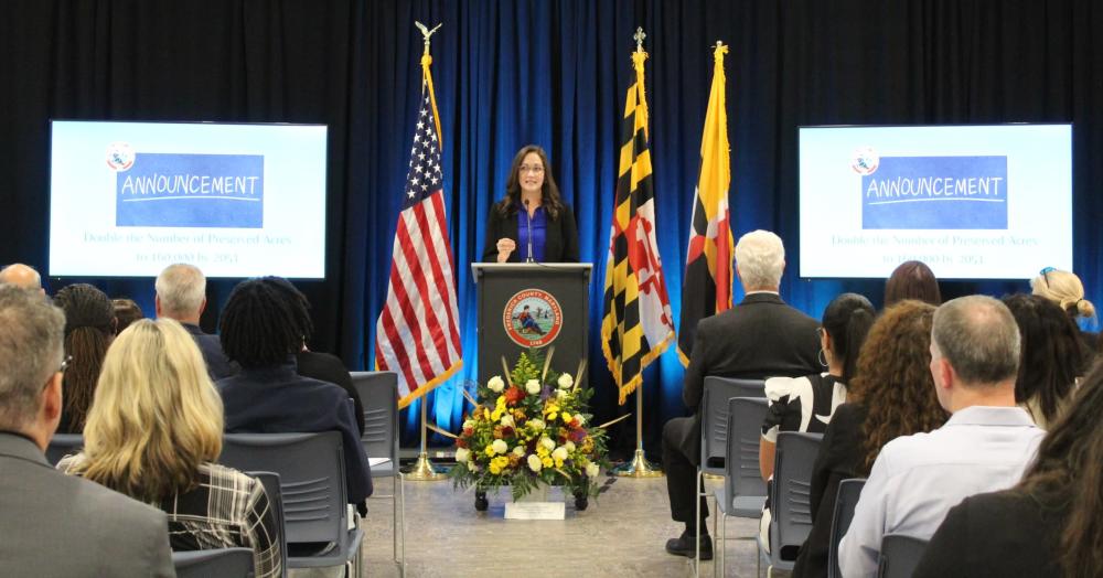 A woman giving a speech in front of an audience.