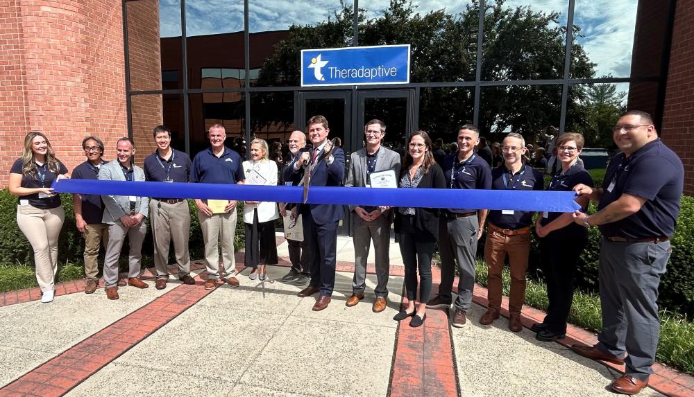 A group of people at a ribbon cutting in front of a building.