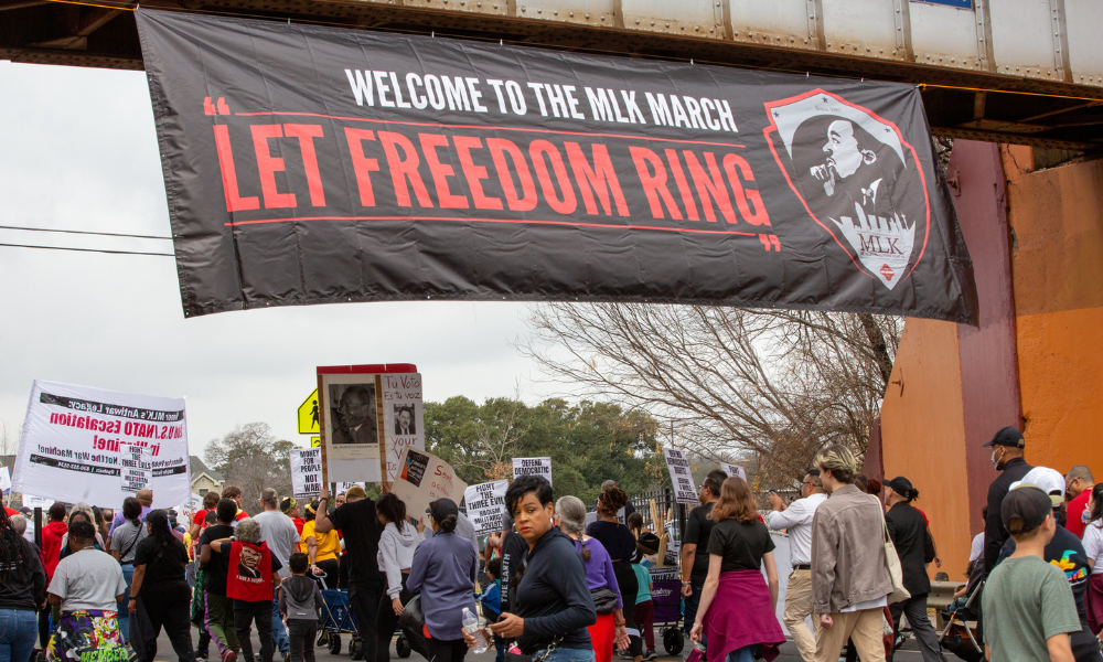 Martin Luther King Jr. March banner hangs on a bridge over marchers