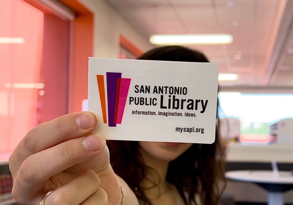 Person holding a library card in their outstretched hand