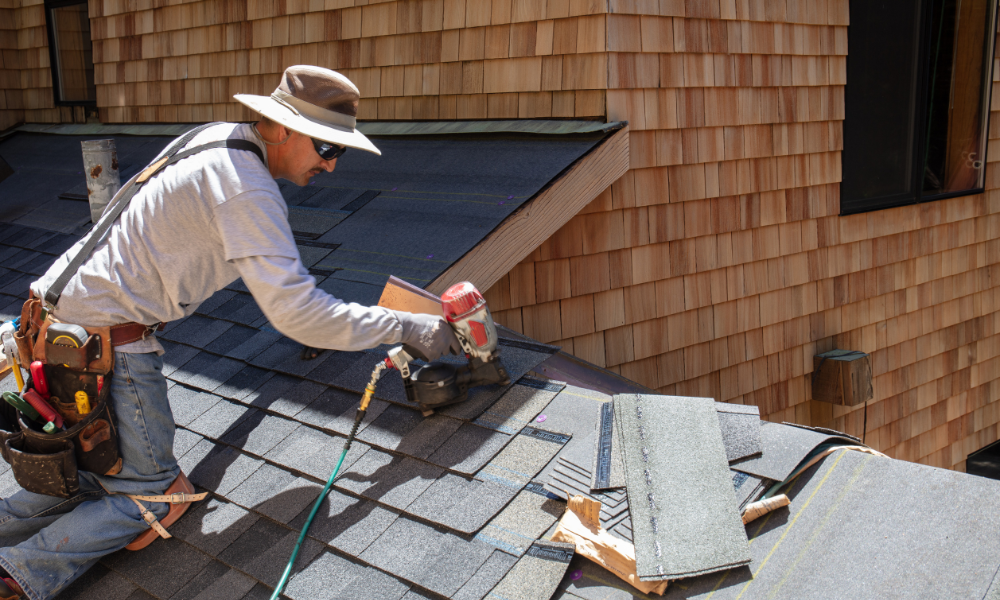 A roofer nailing shingles