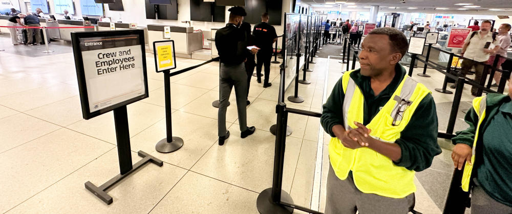 An airport worker wears a yellow vest at the security checkpoint so he is easy to find in the crowds 