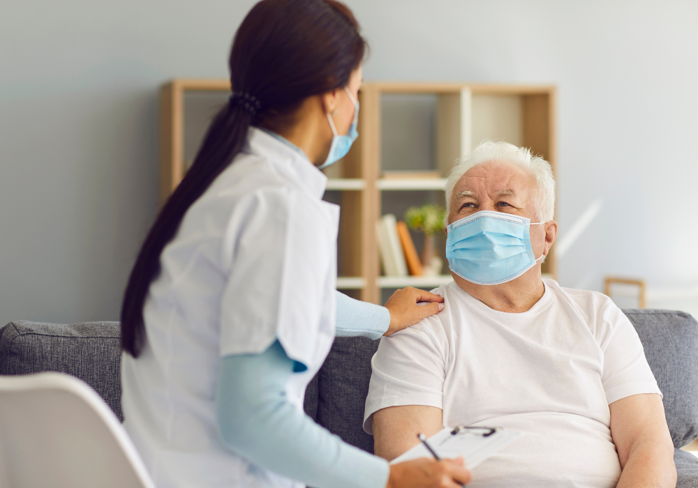 Older adult male patient with a face mask speaking with a female doctor