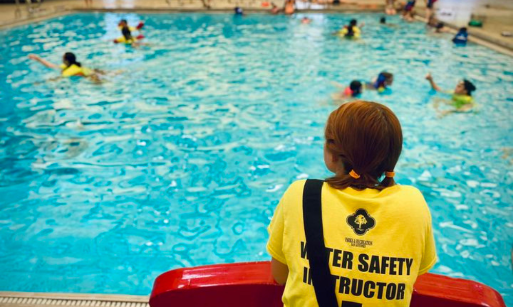 A lifeguard looking at kids swimming