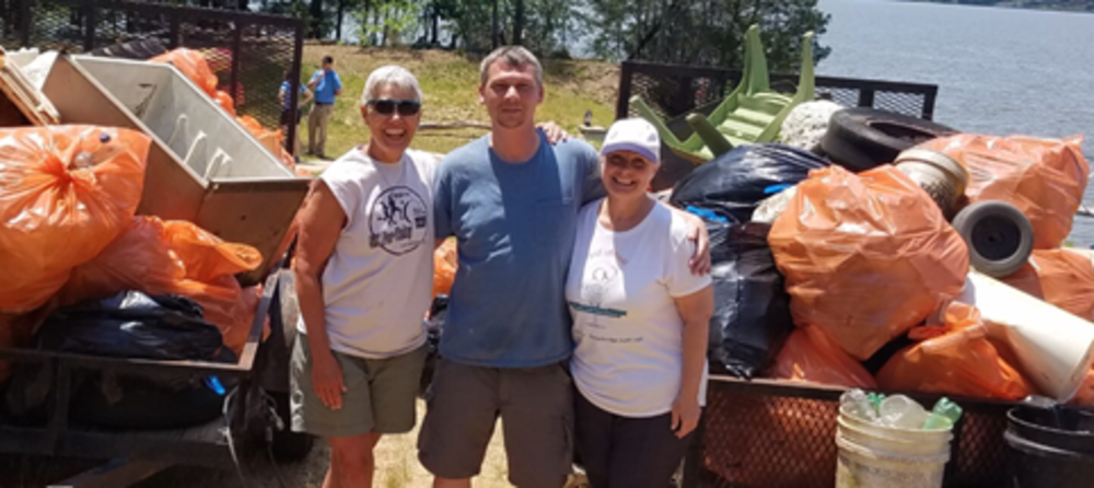 Volunteers cleaning up the river with many bags of trash.