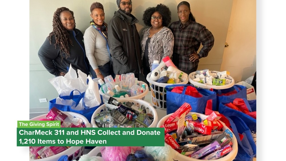 Photo of 311 staff posing in front of donated items to Hope Haven.