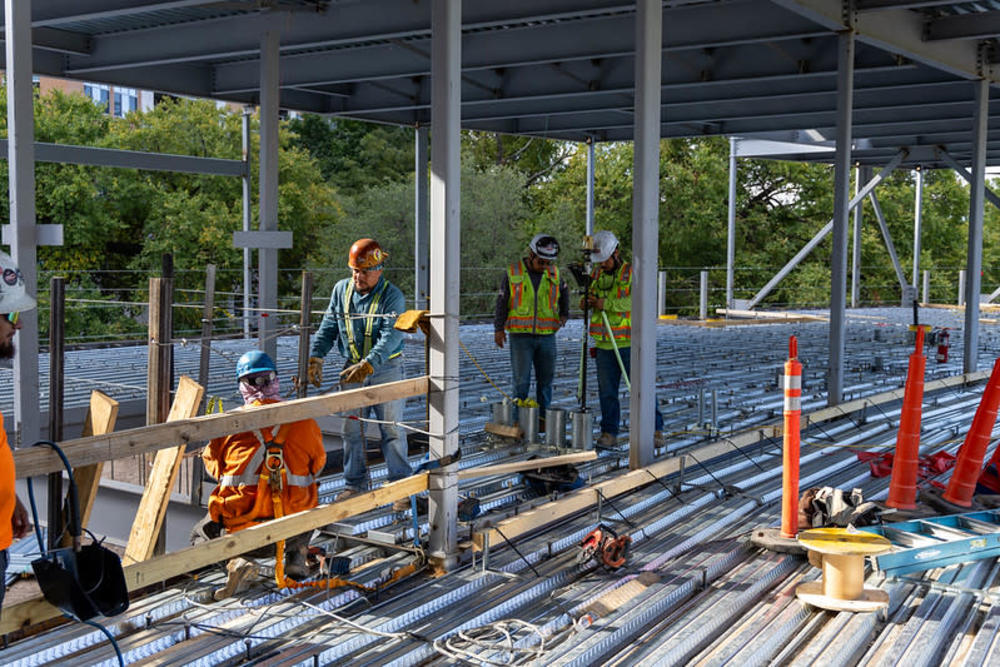 Image of Capital Delivery Services construction project crews working in an active construction site with safety cones and engineers confirming project standards.