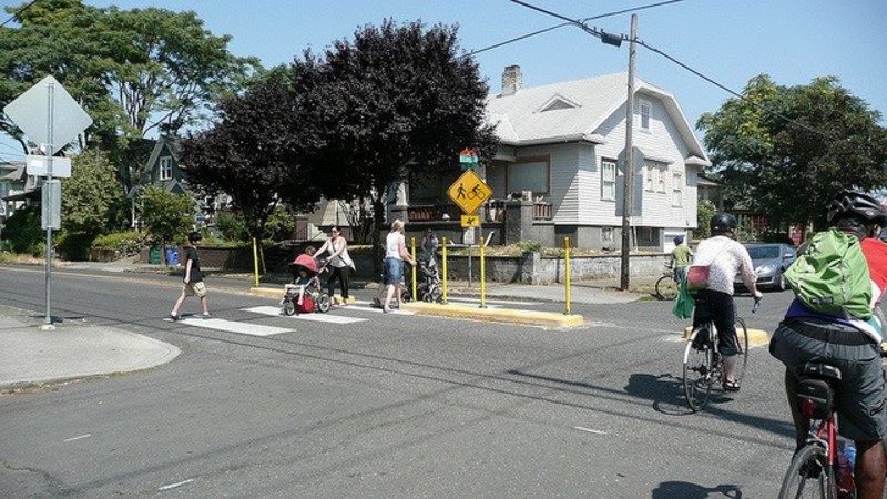 Street crossing with a bicycle boulevard (signs markings and traffic calming) with people riding bikes and walking